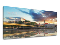 Класична слика на платно со мотив ПАНОРАМА СЛОВАЧКА, замок, река, мост, архитектура во сино-портокалово нијанси, мирна атмосфера, погоден за ходник – главна